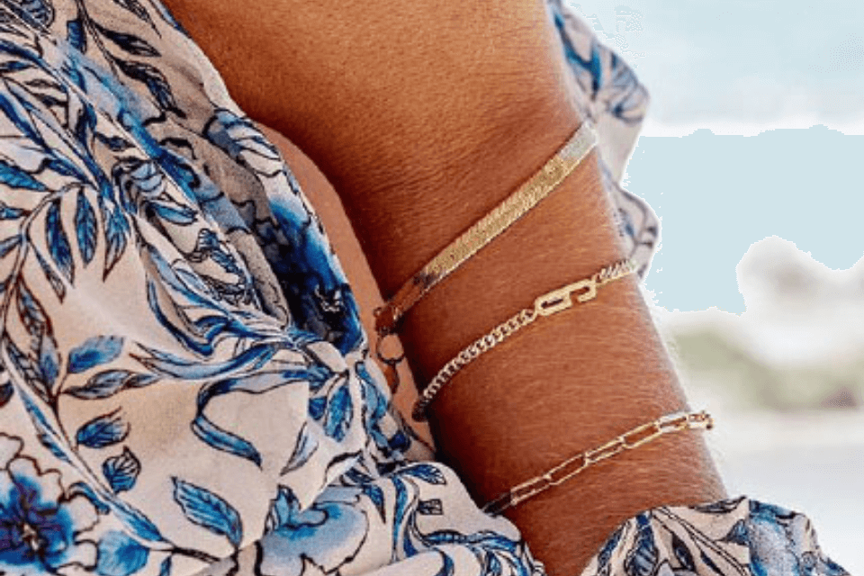 a close up of a woman's wrist wearing gold bracelets